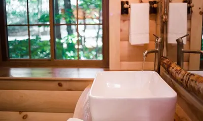 a white sink in a bathroom with a window at Treehouse #3 by Amish Country Lodging in Millersburg