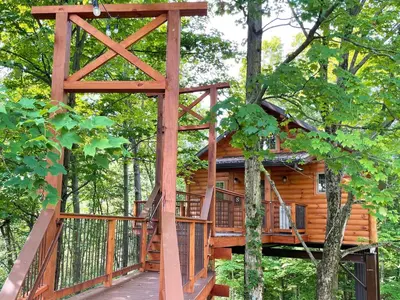a tree house in the woods with a deck at Treehouse #8 by Amish Country Lodging in Millersburg