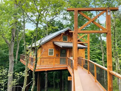 a tree house in the woods with a walkway at Treehouse #7 by Amish Country Lodging in Millersburg