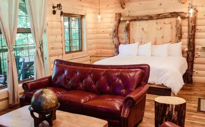 a bedroom with a bed and a leather couch at Treehouse #7 by Amish Country Lodging in Millersburg