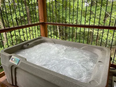 a hot tub on a balcony with a fence at Treehouse #7 by Amish Country Lodging in Millersburg