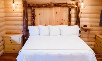 a bedroom with a white bed in a log cabin at Treehouse #6 by Amish Country Lodging in Millersburg