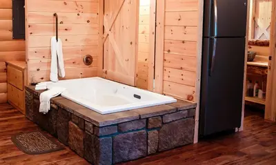 a bath tub in a room with a refrigerator at Treehouse #6 by Amish Country Lodging in Millersburg