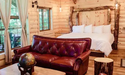 a bedroom with a bed and a leather couch at Treehouse #4 by Amish Country Lodging in Millersburg