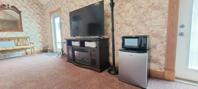 a living room with a tv and a refrigerator at Victorian Suite by Amish Country Lodging in Millersburg