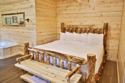 a bedroom in a log cabin with a bed and a tub at Waterview Lodge by Amish Country Lodging in Millersburg