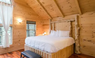 a bedroom with a bed in a log cabin at Whispering Pines Treehouse by Amish Country Lodging in Millersburg