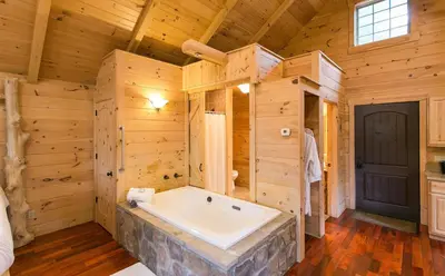 a large bathroom with a tub in a wooden house at Whispering Pines Treehouse by Amish Country Lodging in Millersburg