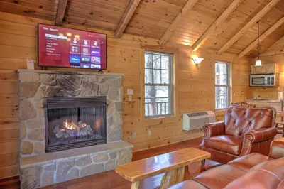 a living room with a fireplace and a tv at Whispering Pines Treehouse by Amish Country Lodging in Millersburg