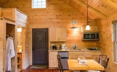 a kitchen with a table in a wooden cabin at Whispering Pines Treehouse by Amish Country Lodging in Millersburg
