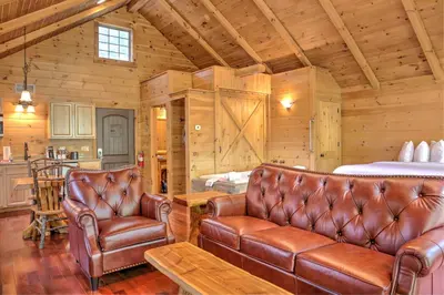 a living room with leather furniture in a log cabin at Whispering Pines Treehouse by Amish Country Lodging in Millersburg