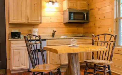 a kitchen with a wooden table and two chairs at Whispering Pines Treehouse by Amish Country Lodging in Millersburg