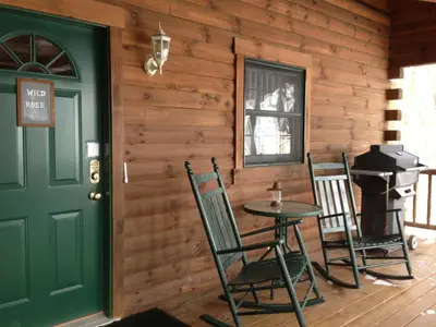 a porch with a green door and two chairs and a table at Wild Rose Cabin by Amish Country Lodging in Millersburg