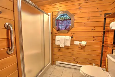 a bathroom with a shower and a toilet at Wild Rose Cabin by Amish Country Lodging in Millersburg