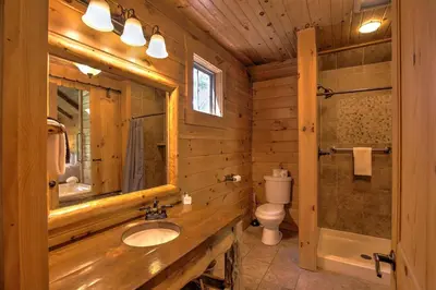 a bathroom with a sink and a toilet and a mirror at Wild Cherry Treehouse by Amish Country Lodging in Millersburg