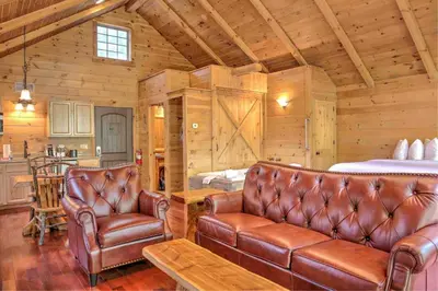a living room with two leather chairs and a bed at Wild Cherry Treehouse by Amish Country Lodging in Millersburg