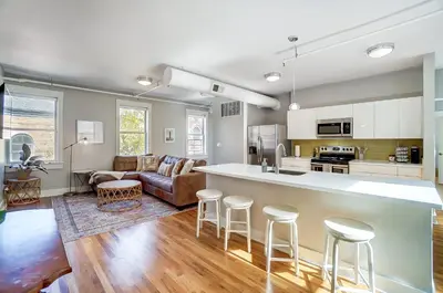 a kitchen and living room with a counter and stools at The Republic Retreat Walk to Washington Park! in Cincinnati
