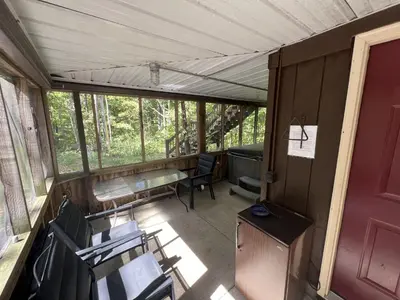 a screened in porch of a house with chairs and a table at Rock Stalls Lodge in Logan