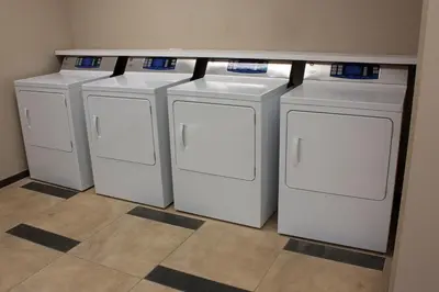 a row of four washing machines in a room at Candlewood Suites Youngstown W - I-80 Niles Area by IHG in Austintown