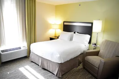 a hotel room with a bed and a chair at Candlewood Suites Youngstown W - I-80 Niles Area by IHG in Austintown