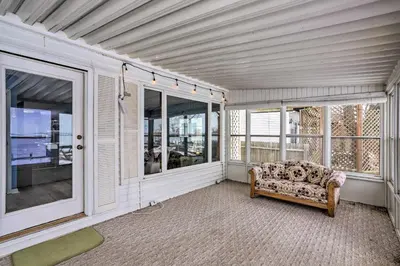 an empty room with a couch and windows at Lake Erie Waterfront Home with Sunroom and Yard! in Erie
