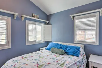 a blue bedroom with a bed and two windows at Lake Erie Waterfront Home with Sunroom and Yard! in Erie