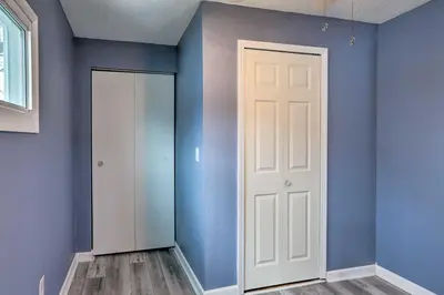 an empty room with a white door and blue walls at Lake Erie Waterfront Home with Sunroom and Yard! in Erie