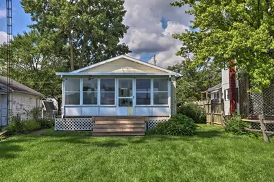 a tiny house in a yard with a fence at Lake Erie Waterfront Home with Sunroom and Yard! in Erie