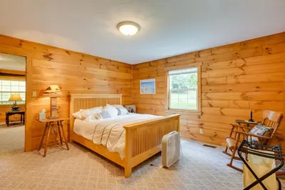 a bedroom with a bed in a room with wooden walls at Serene Mountain Retreat on 40 Acres with Fire Pit! in Bomont