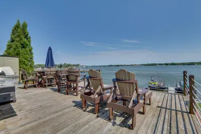 a dock with chairs and a table and a television at Lakefront Home with Rooftop Deck, Grill, Games! in Hebron