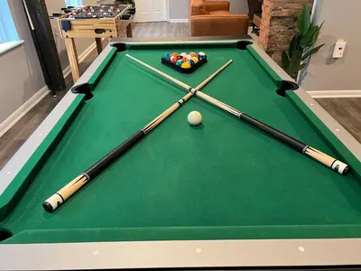 three cue sticks and a ball on a pool table at **Stylish Pet Friendly 3 Bedroom House** in Cleveland