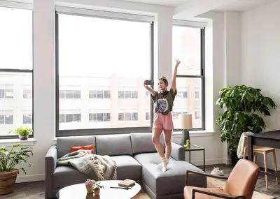 a girl jumping on a couch in a living room at ROOST Cleveland in Cleveland