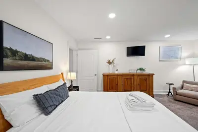 a bedroom with a large white bed and a chair at Gather Together - Charming Home for 20 Near Ark! in Williamstown
