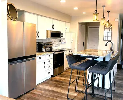 a kitchen with a refrigerator and a counter with bar stools at Harborview 3-6-8 on Main in Huron