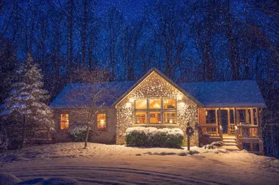 a house covered in christmas lights in the snow at Cherry Ridge Retreat Luxury Cabins in New Plymouth