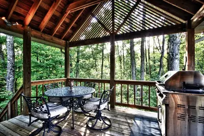 a screened in porch with a table and a grill at Cherry Ridge Retreat Luxury Cabins in New Plymouth