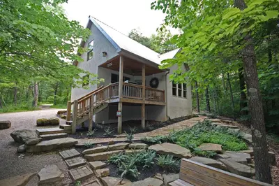 a house with a porch and a deck in the woods at Cherry Ridge Retreat Luxury Cabins in New Plymouth