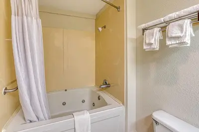 a bathroom with a tub and a shower curtain at American Inn & suites in Dundee