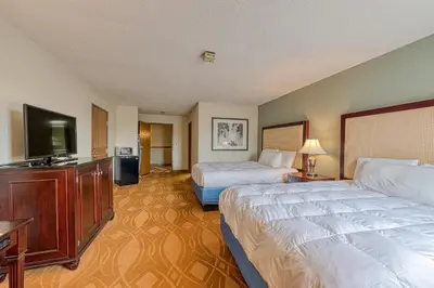 a hotel room with two beds and a flat screen tv at American Inn & suites in Dundee