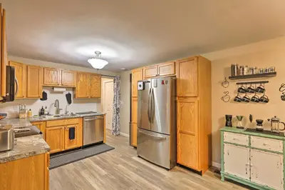 a kitchen with wooden cabinets and a stainless steel refrigerator at Single-Story Home in Fairborn with Yard and Patio! in Fairborn