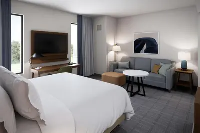 a hotel room with a bed and a couch and a television at Staybridge Suites - Cincinnati East - Milford by IHG in Cincinnati