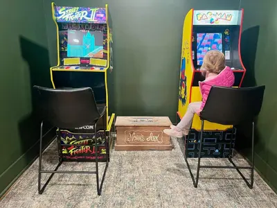 a little girl playing a video game on a pinball machine at Spacious Home Near Ark, Perfect for 12 Guests in Williamstown