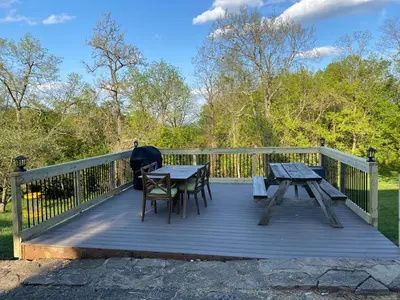 a wooden deck with a table and chairs on it at Spacious Home Near Ark, Perfect for 12 Guests in Williamstown