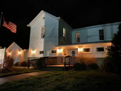 a house with lights on the front of it at night at Spacious Home Near Ark, Perfect for 12 Guests in Williamstown