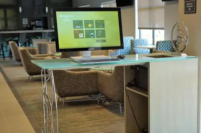 a computer monitor sitting on a desk with chairs at Residence Inn by Marriott Akron South/Green in Akron