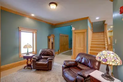 a living room with a leather couch and stairs at Spacious McArthur Home Private Hot Tub and Pond! in Hamden