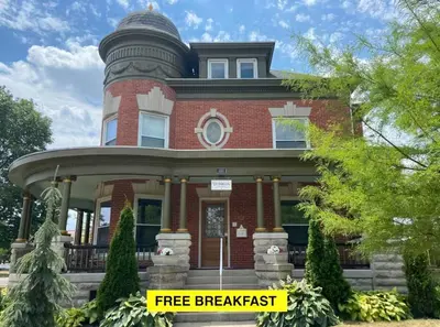 a red brick house with a fire breach sign in front at The Victorian Guesthouse Bed & Breakfast in Delphos
