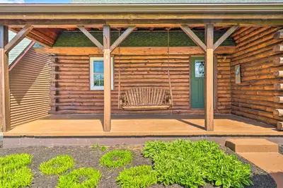 a porch of a log cabin with a swing at Rustic Zanesville Getaway with Expansive Yard! in Zanesville