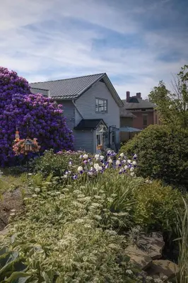 a garden with purple flowers in front of a house at The Carriage House 1836 in Millersburg