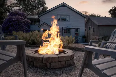 a fire pit in front of a house with two chairs at The Carriage House 1836 in Millersburg